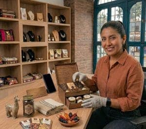 Cesta de productos artesanales y regalos ecológicos en tienda de mercado medio, mujer mostrando prod.